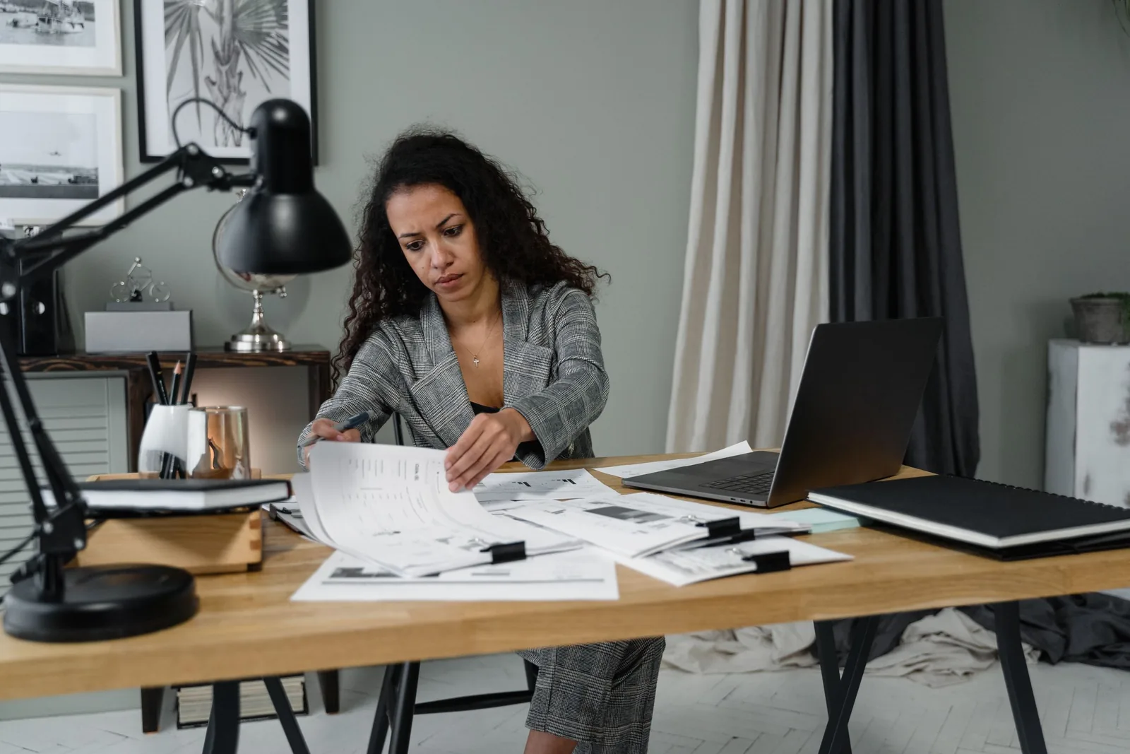 Business owner working through paperwork at a desk with a laptop